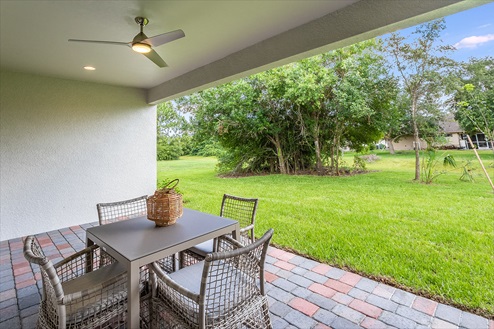 Outside of the Kellen model. Mixed paver patio with a four-person dining table and fan.