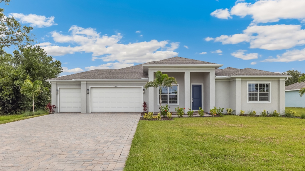 Outside of the Kellen model. Off-white home with three car garage, two windows, and front door. Mixed pavers driveway.