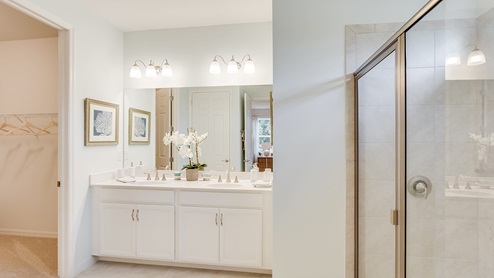 Inside of the Kellen model bathroom. Tile flooring and white walls. Double vanity and white cabinets with silver hardware. Shower has grey tile and silver hardware.