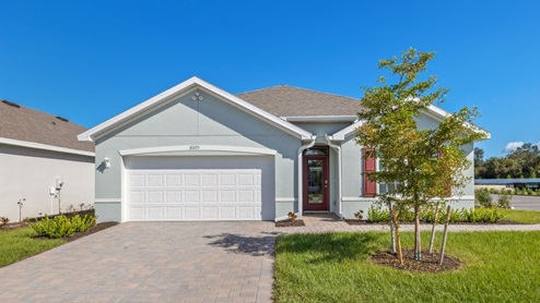 Outside of the Cali model C home. Blue home, two car garage, window with shutters, and front door. Mixed paver driveway.