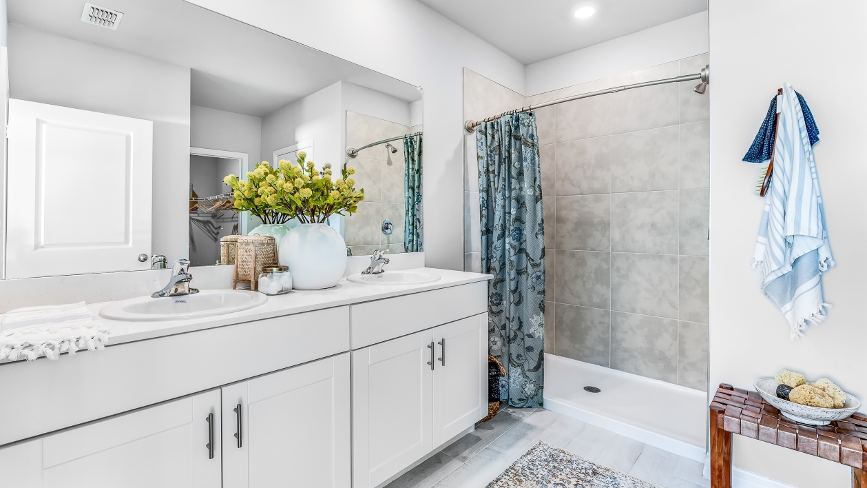The Master Bathroom has a tiled shower with white cabinetry and silver fixtures. There is plenty of space for two people with the dual sink counter.