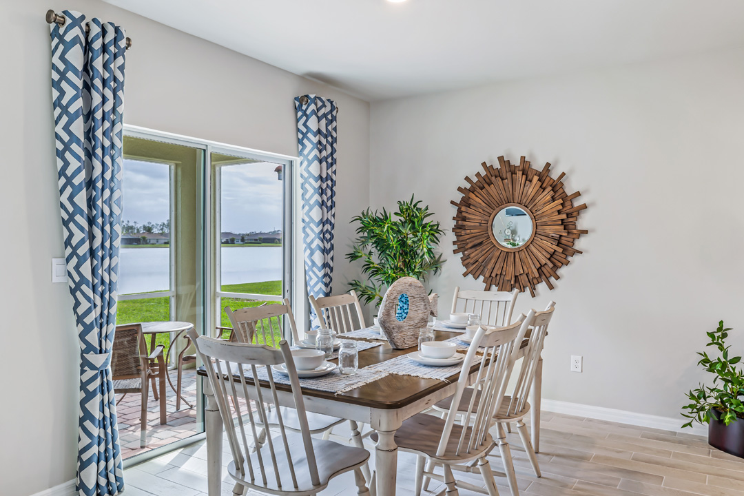 Inside of the Cali model dining room. Contains the six-person dining table and chairs. In the background the back patio with two rocking chairs can be seen.