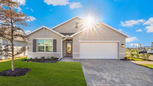 Exterior elevation of tan home with white trim, gray doors, gray shutters and gray paver driveway.