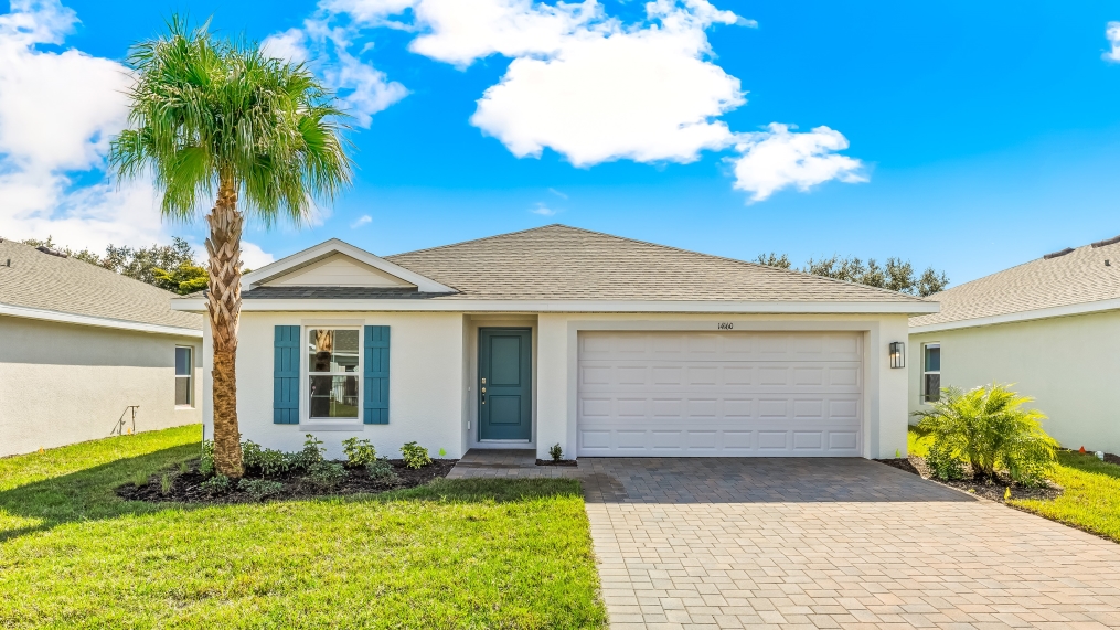 Outside of the Dundee model. Light colored home with a two car garage, one window with shutters, and front door. Mixed pavers driveway.