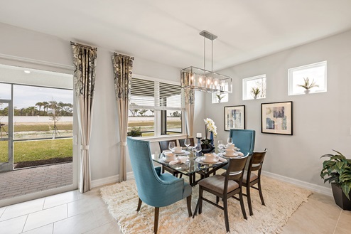Inside the Kellen model dining are. Tile flooring and white walls. Six-person dining table with hanging light fixture. Sliding glass door can be seen in the background.
