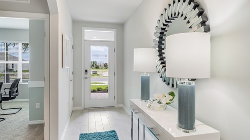 Inside of the Cali model hallway. Wood tile flooring, off-white walls. Hallway to the front door and den area.