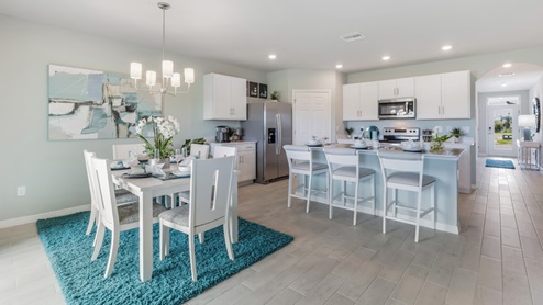 Inside of the Cali model dining area and kitchen. This photo demonstrates how the kitchen and dining area can be seen at all times thanks to the kitchen's open concept. In the background the hallway leading to the front door and other bedrooms can be seen.