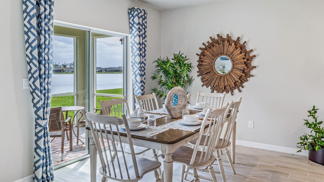 Inside of the Cali model dining room. Contains the six-person dining table and chairs. In the background the back patio with two rocking chairs can be seen.