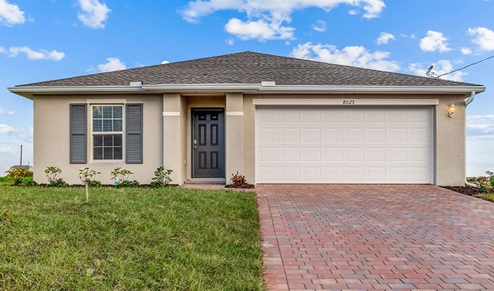 Outside of the Boardwalk B model. Yellow home with two car garage, window with shutters, and front door. Mixed paver driveway.