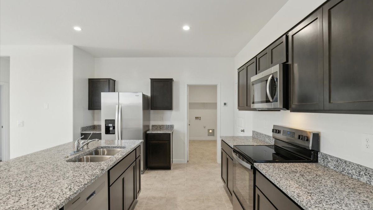 Bright and spacious kitchen with granite countertops, stainless steel appliances, and an island with bar seating.