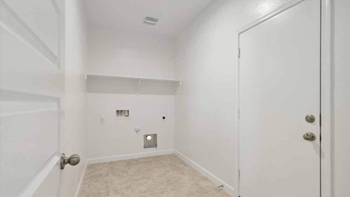 Spacious laundry room with washer and dryer connections and shelving for storage.