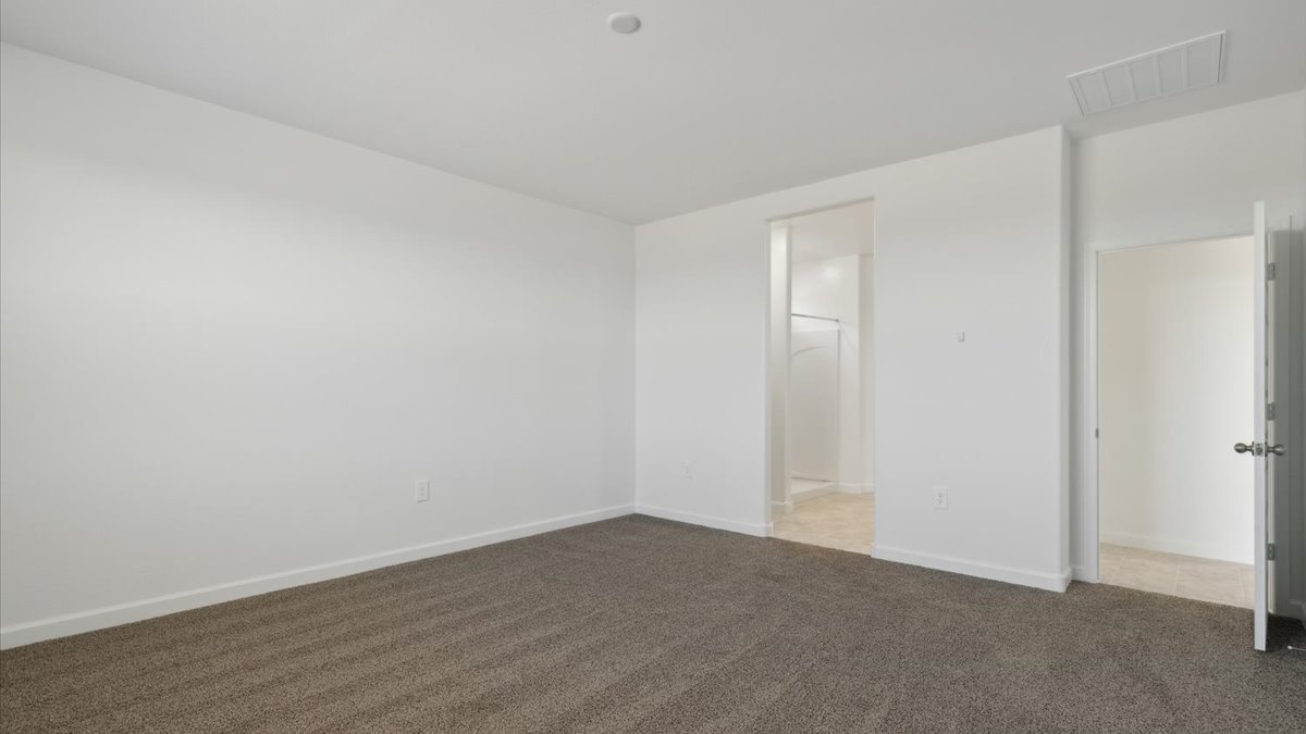 A spacious primary bedroom emphasizing open space and natural lighting.