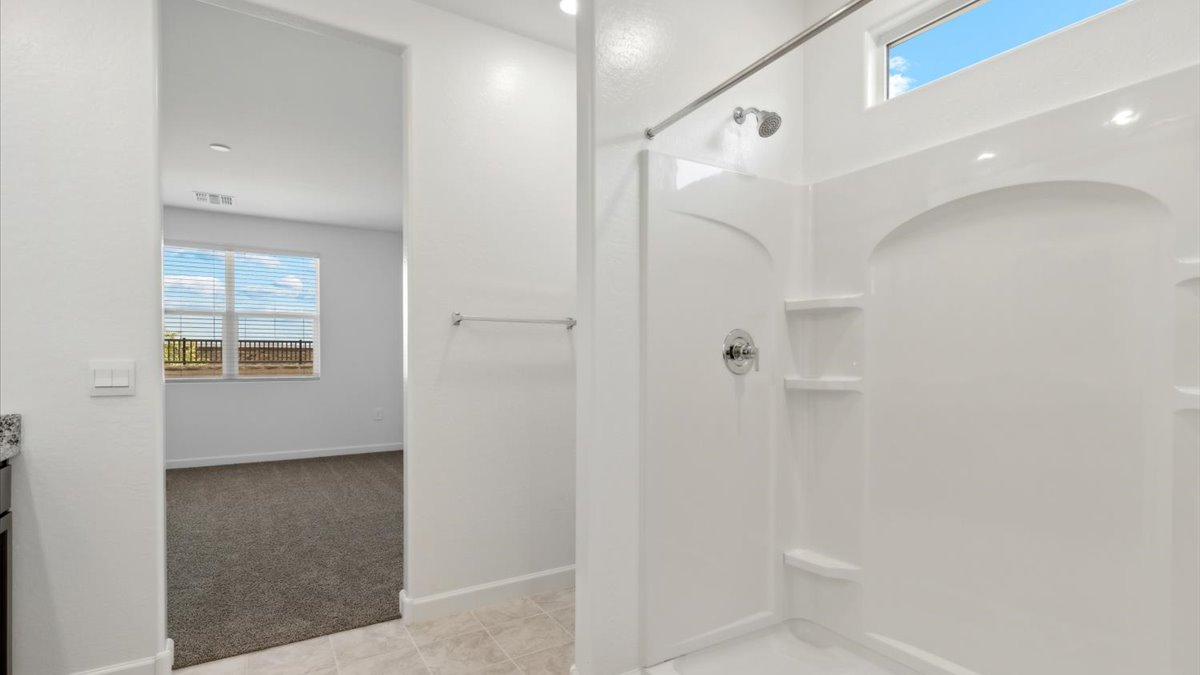 Modern primary bathroom with double vanity, granite countertops with a walk-in shower and a walk-in closet.