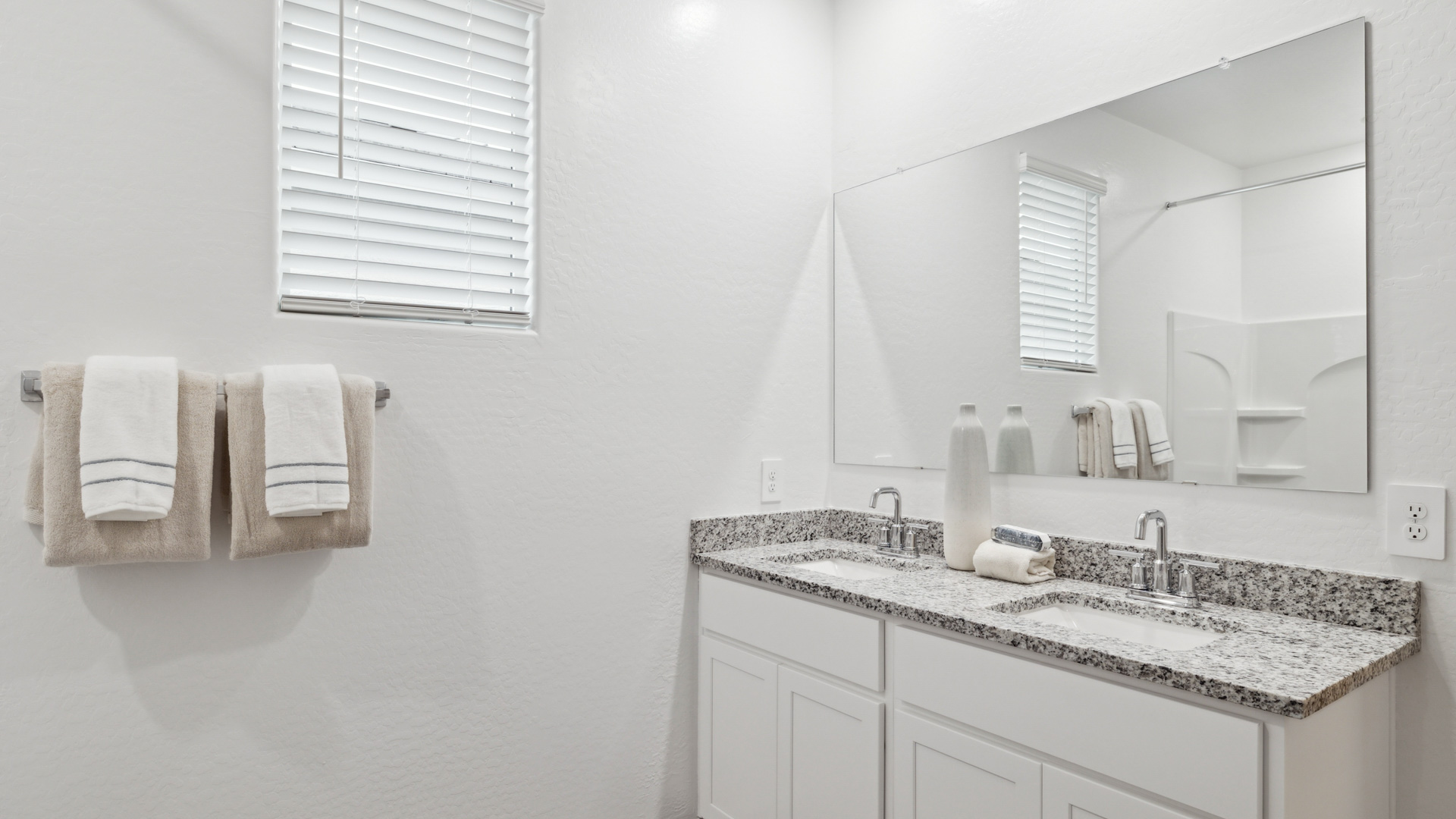 Modern primary bathroom with double vanity, granite countertops with a walk-in shower and a walk-in closet.