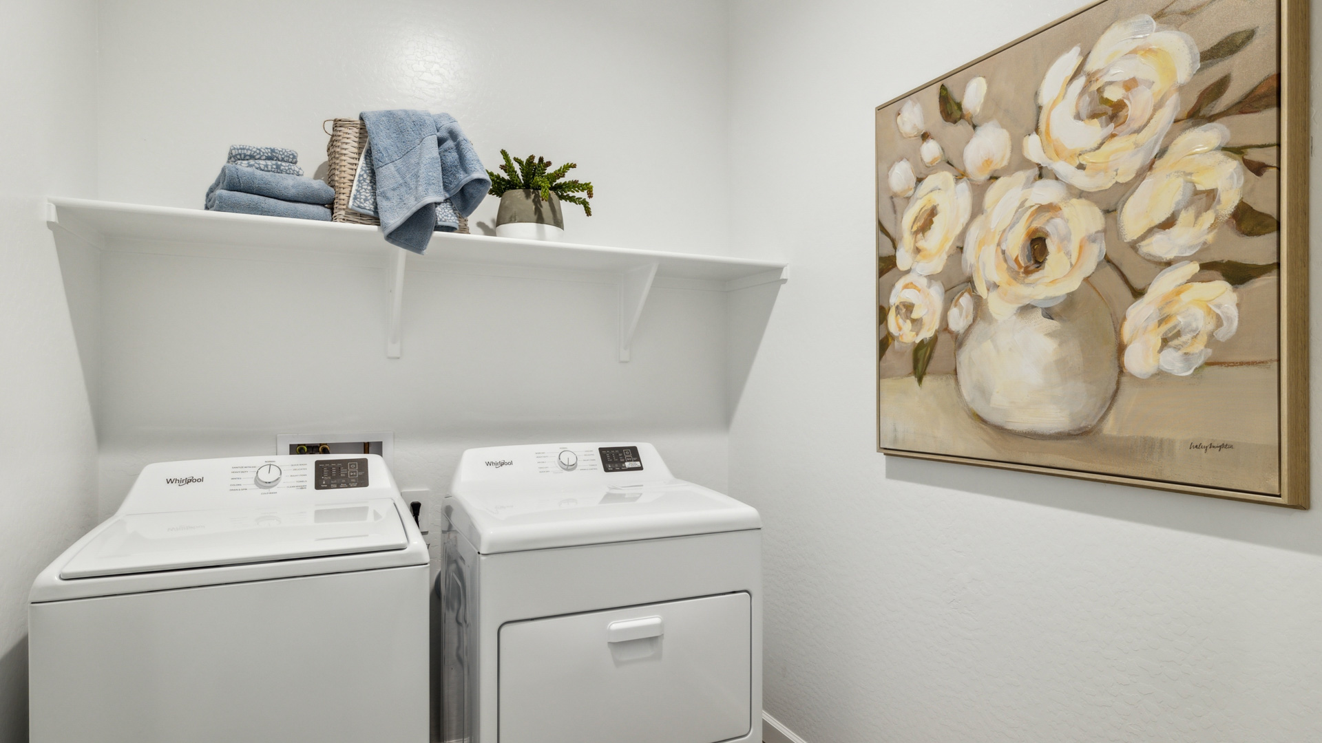 Spacious laundry room with washer and dryer connections and shelving for storage.