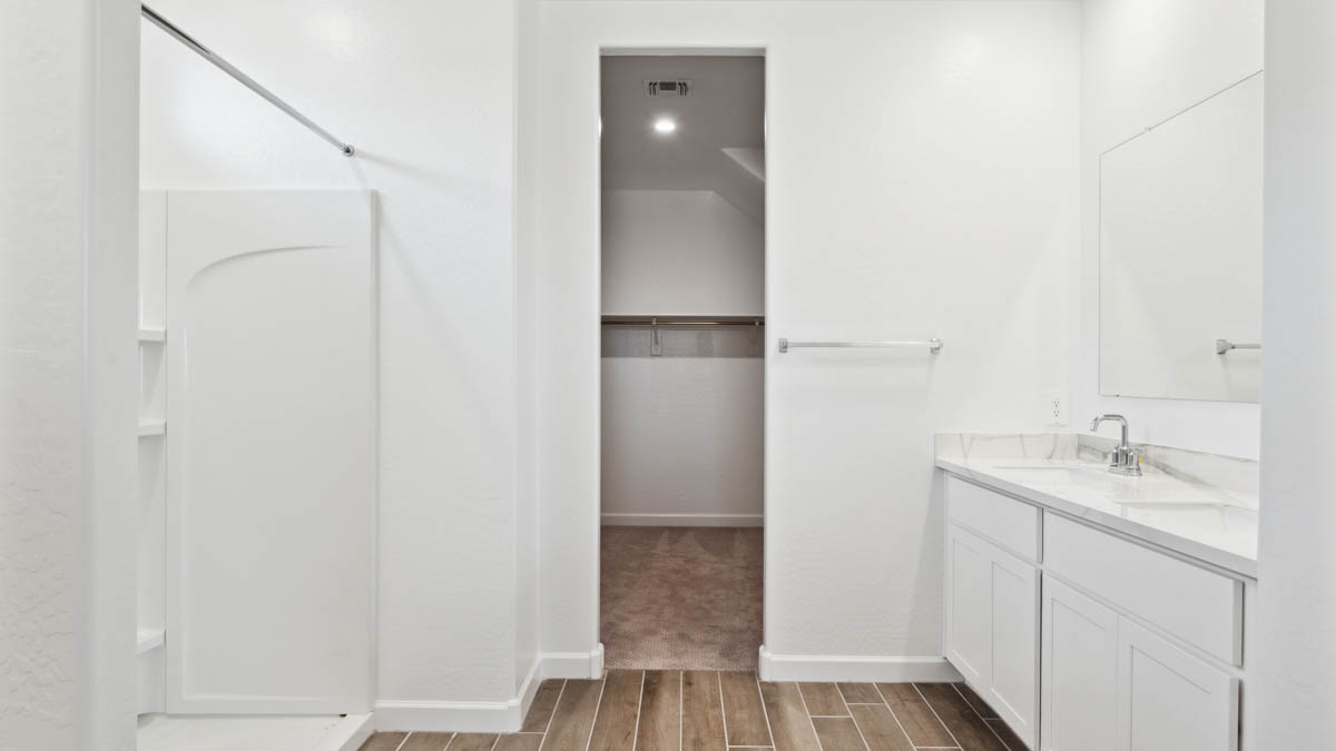 Modern primary bathroom with double vanities, with a walk-in shower and a walk-in closet.