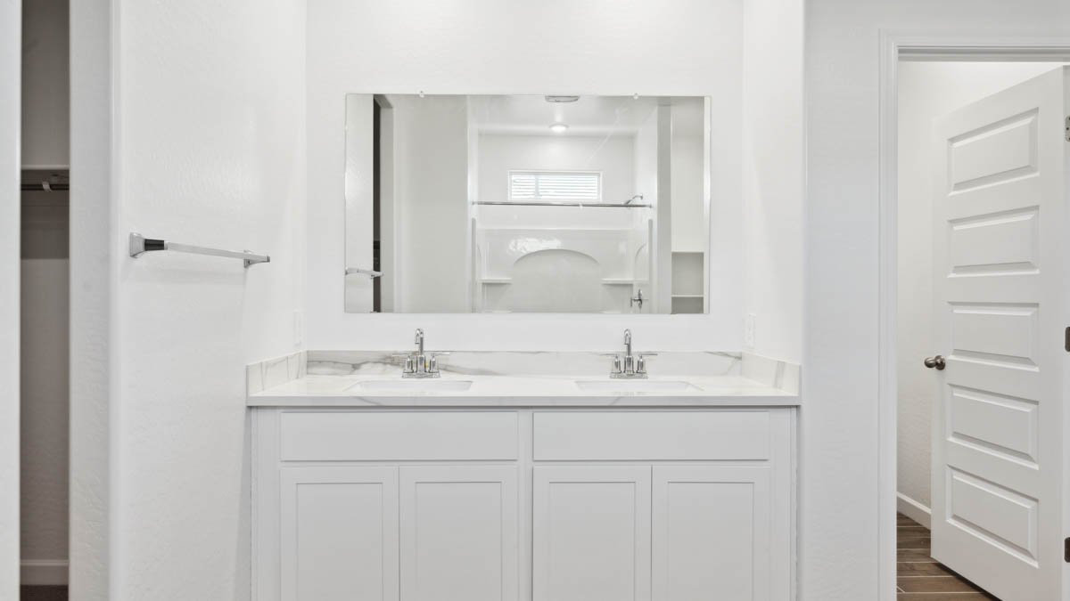 Modern primary bathroom with double vanities, with a walk-in shower and a walk-in closet.