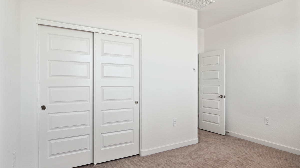 Upstairs bedroom featuring neutral-toned walls, carpeted flooring, and a large closet.