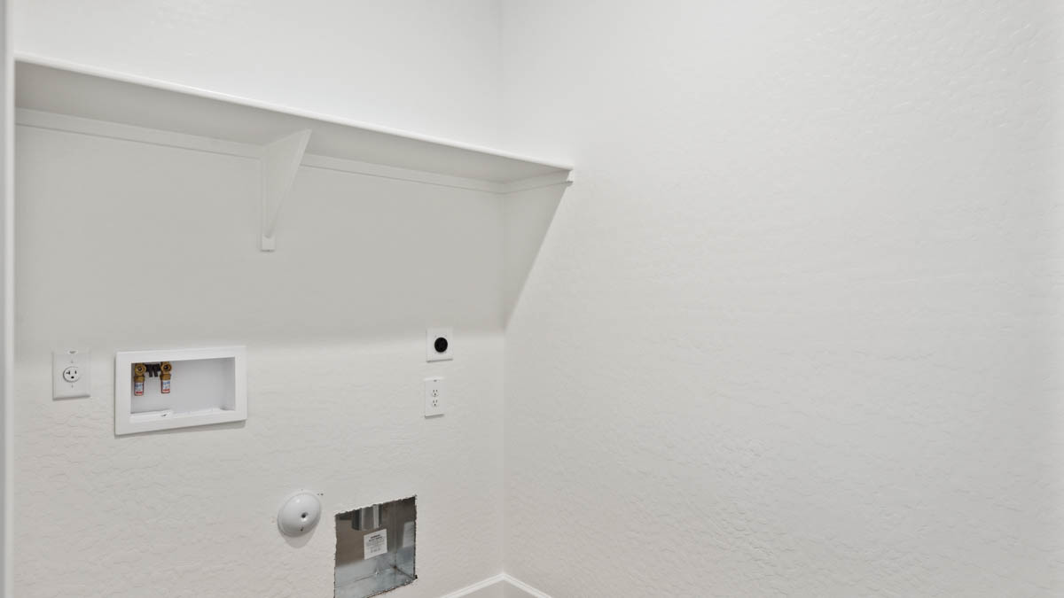 Spacious laundry room with washer and dryer connections and shelving for storage.