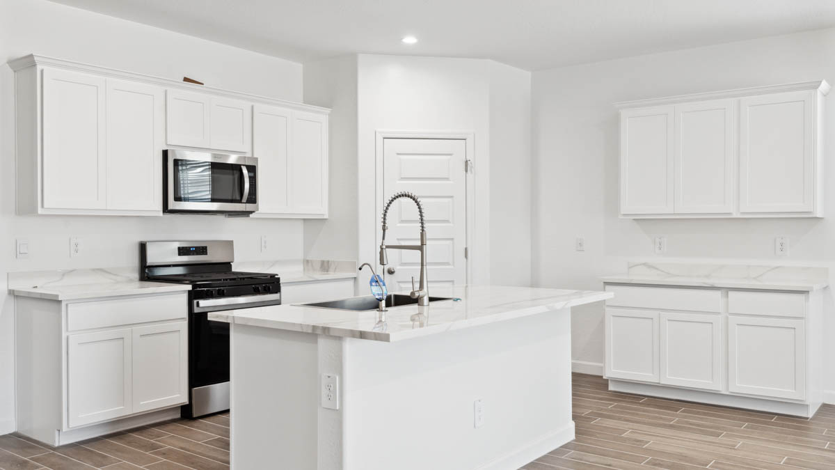 Bright and spacious kitchen with countertops, stainless steel appliances, and an island with bar seating.