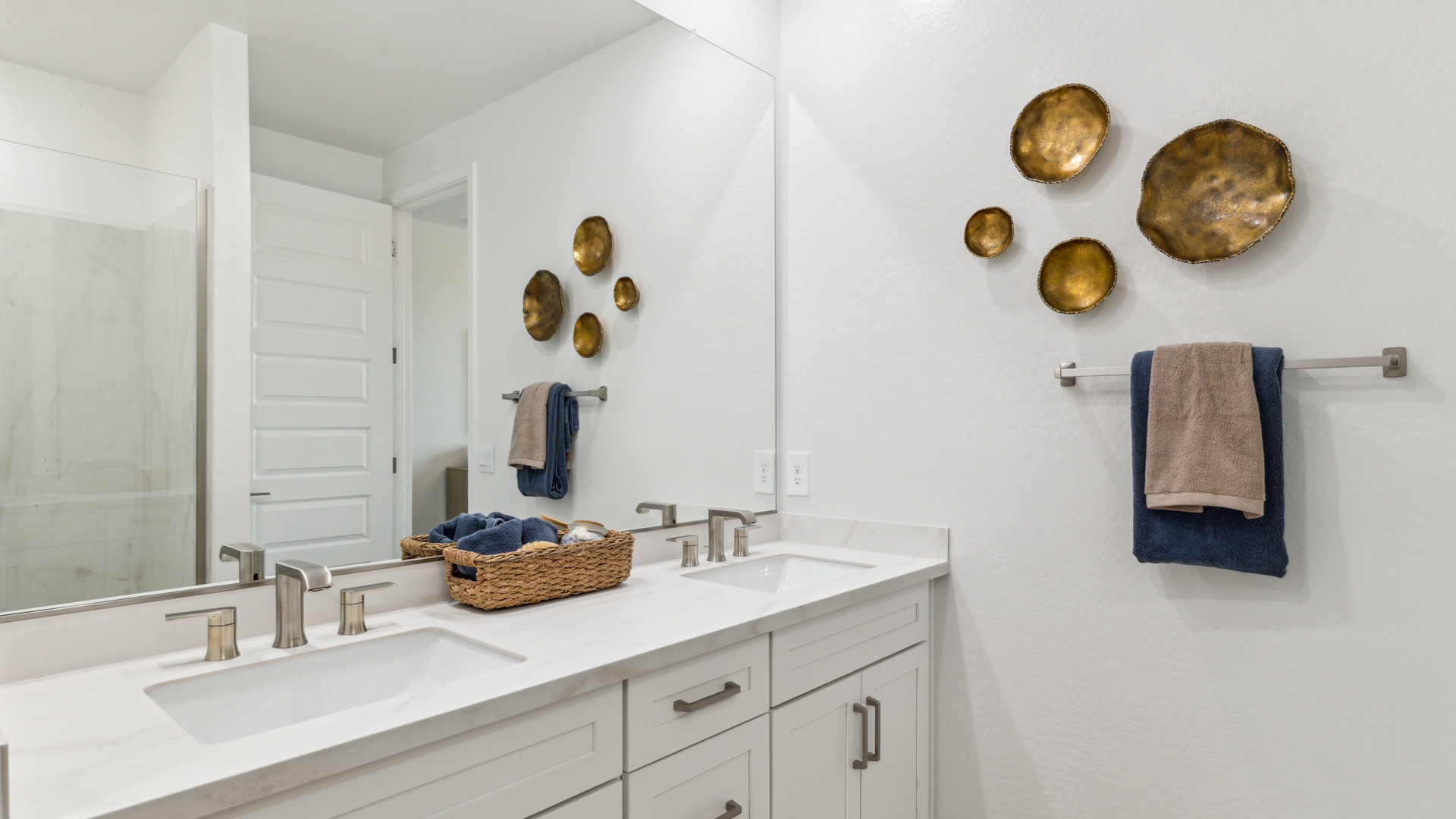Modern primary bathroom with double vanities, quartz countertops with a walk-in shower and a walk-in closet.