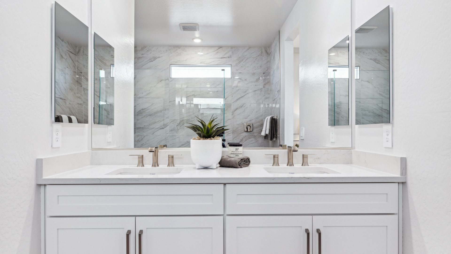 Modern primary bathroom with double vanities, quartz countertops with a walk-in shower and a walk-in closet.