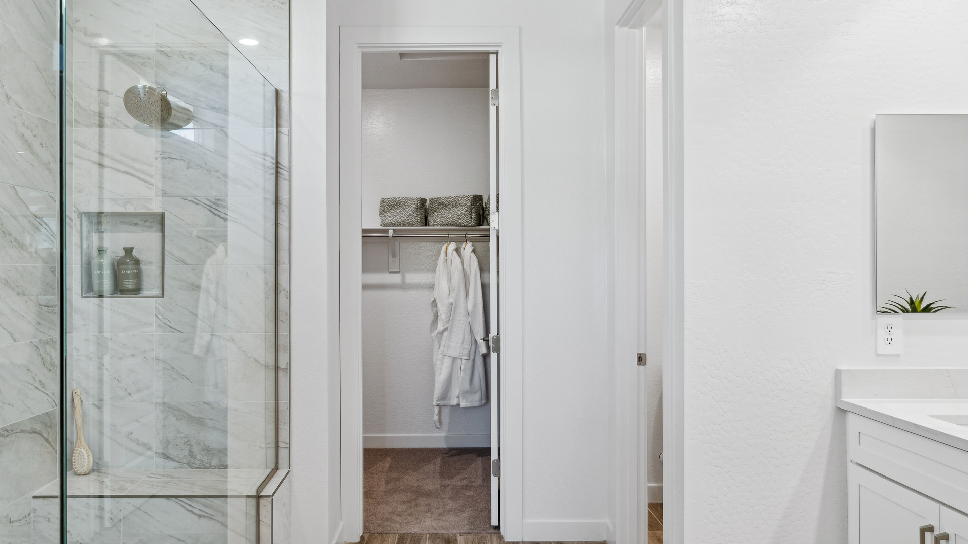 Modern primary bathroom with double vanities, quartz countertops with a walk-in shower and a walk-in closet.