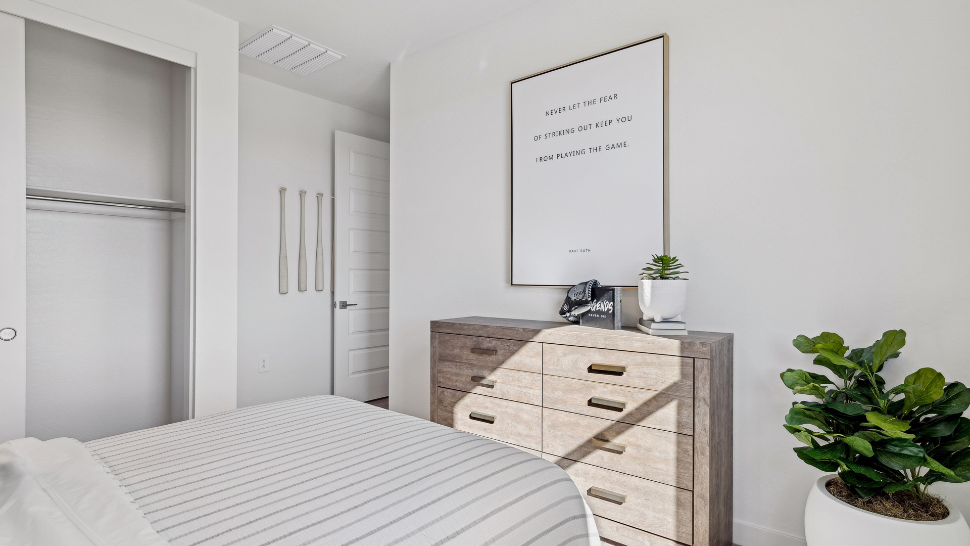 A vibrant kids' bedroom showcasing a neatly made bed, a stylish dresser, and a playful painting that adds charm.