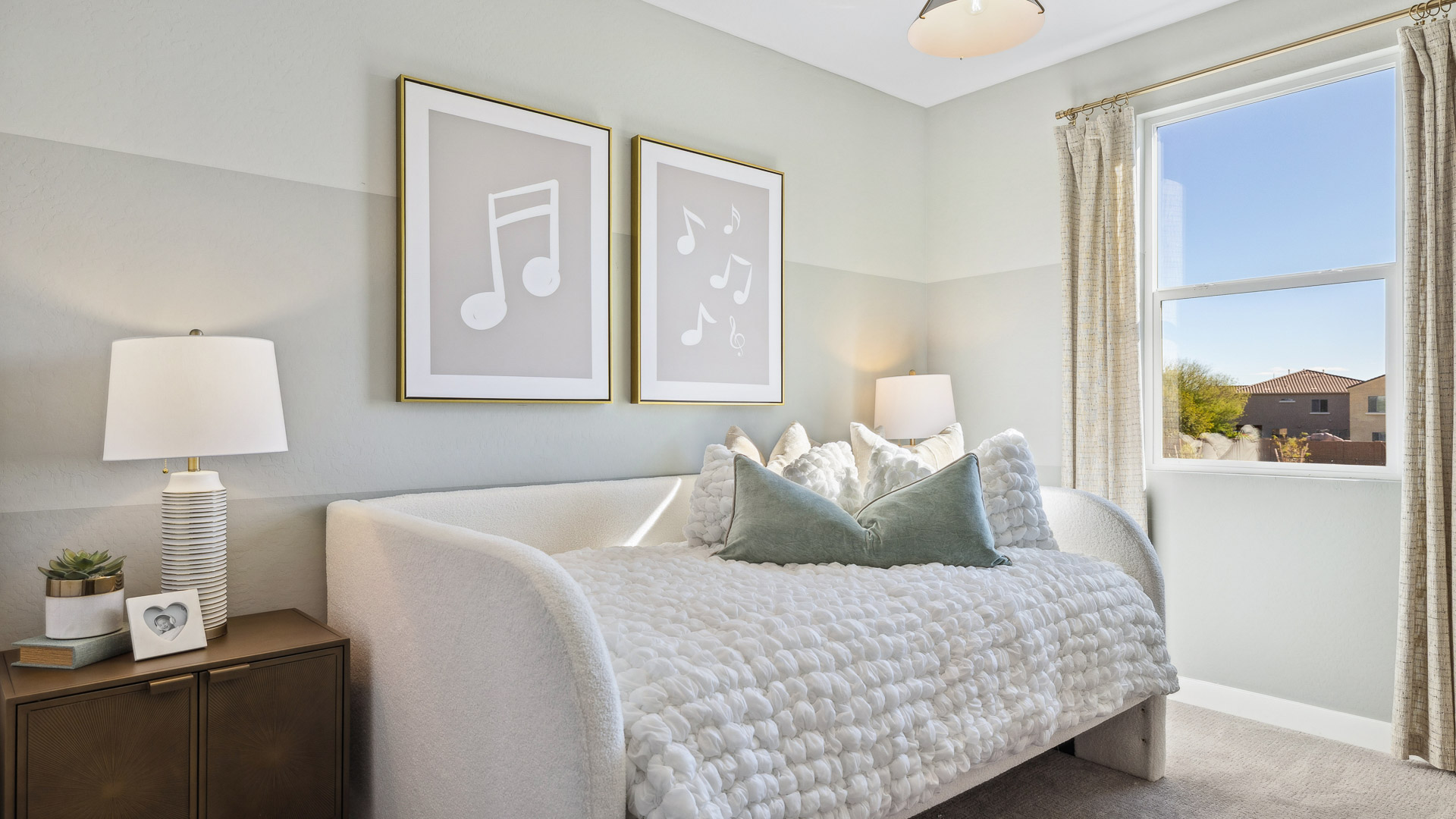 A vibrant kids' bedroom showcasing a neatly made bed, a stylish dresser, and a playful painting that adds charm.