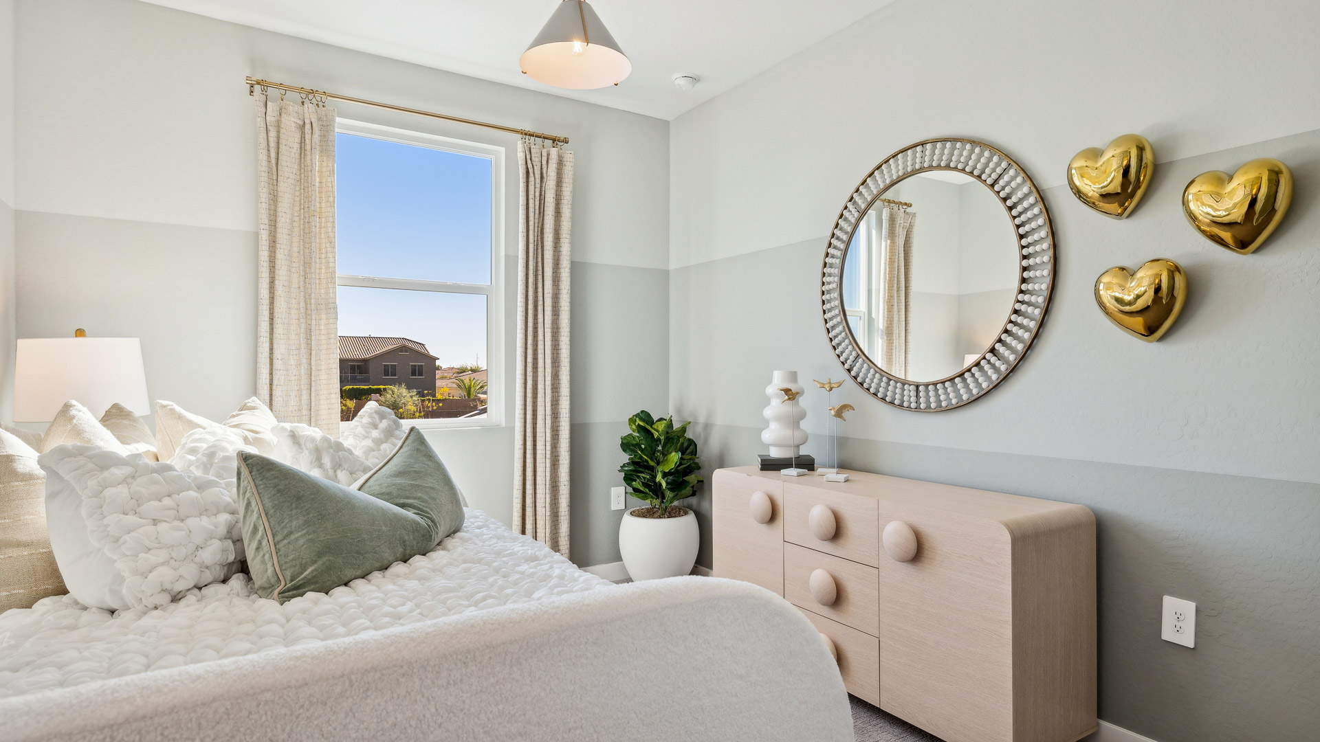 A vibrant kids' bedroom showcasing a neatly made bed, a stylish dresser, and a playful painting that adds charm.