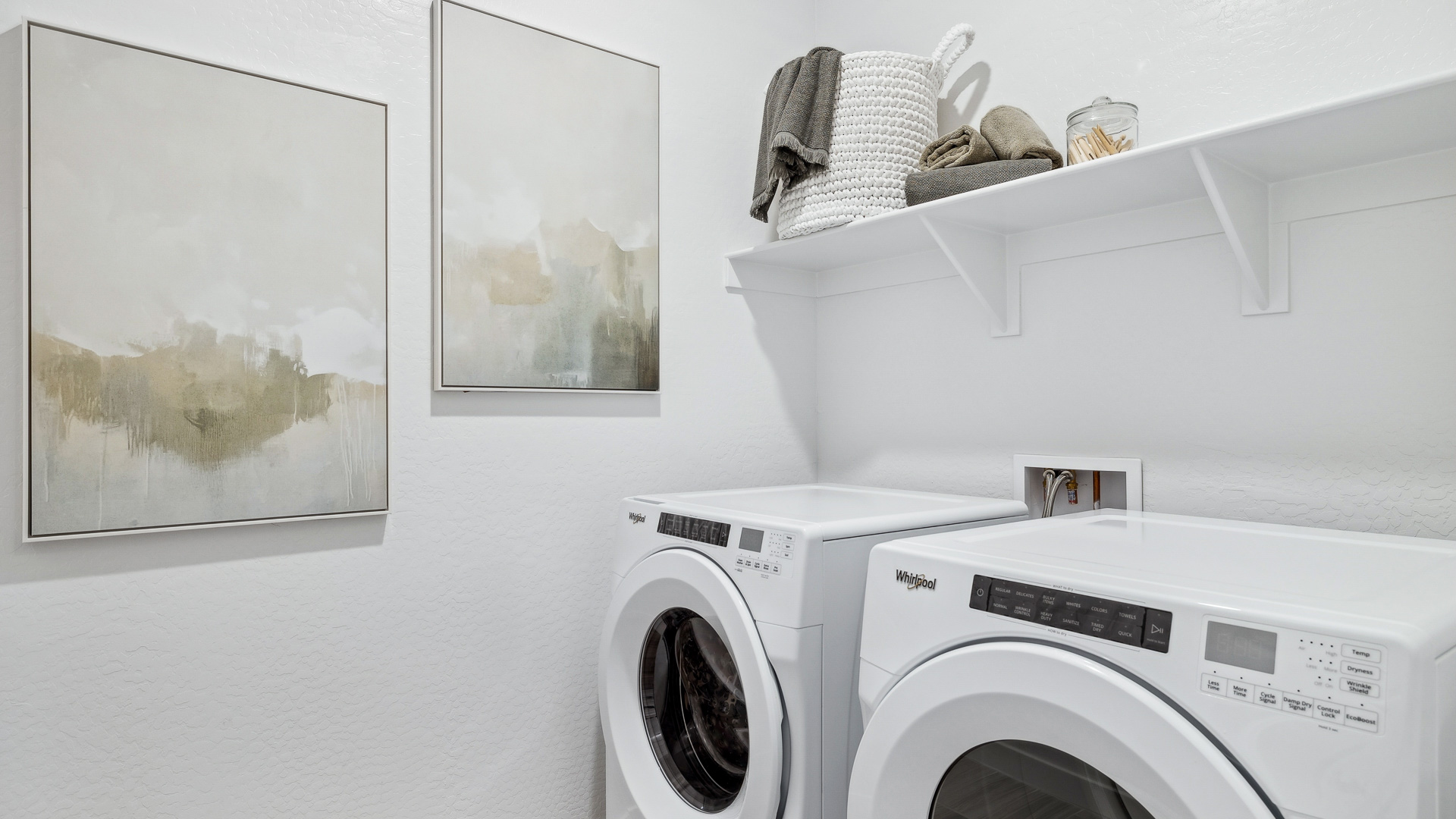 Spacious laundry room with washer and dryer connections and shelving for storage.