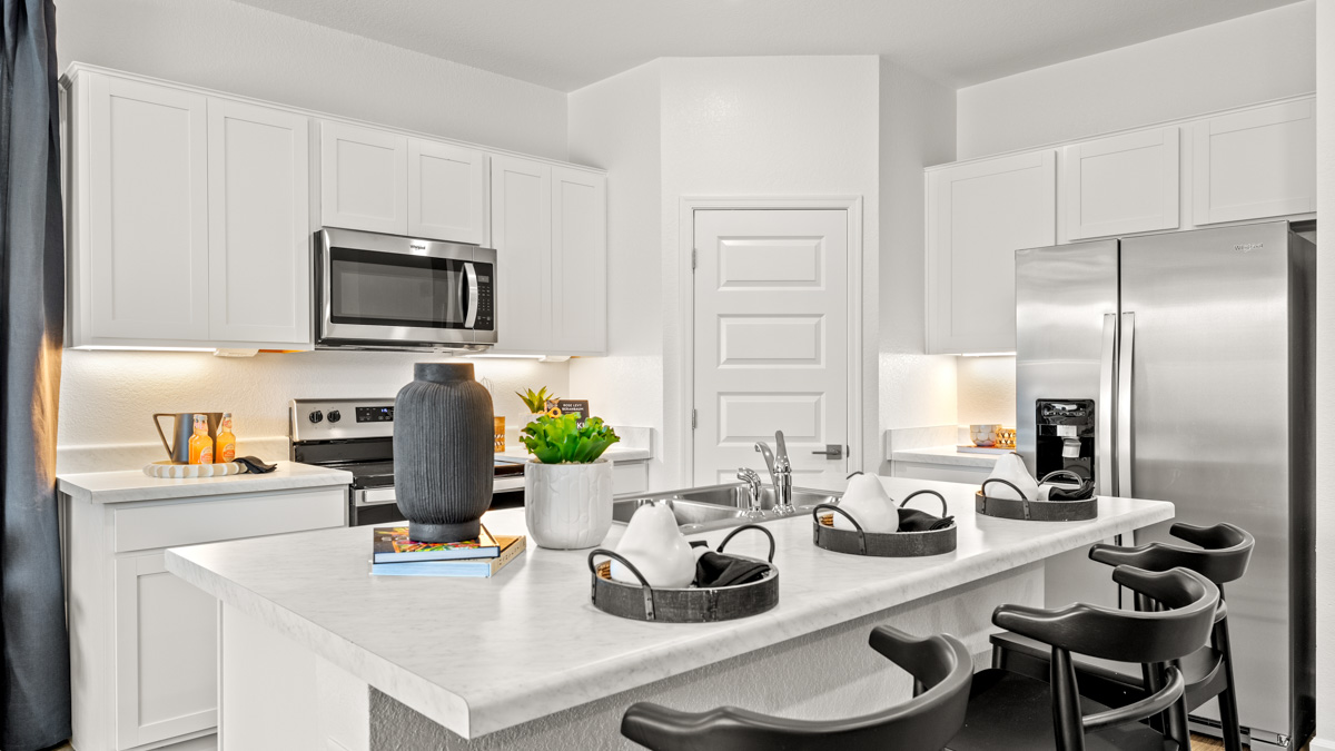 Bright and spacious kitchen with quartz countertops, stainless steel appliances, and an island with bar seating.