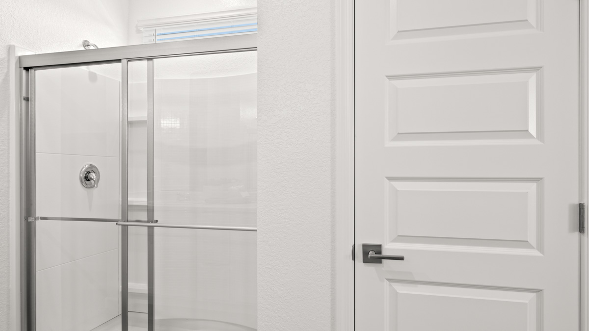 Modern primary bathroom with double vanities, porcelain countertops with a walk-in shower and a walk-in closet.
