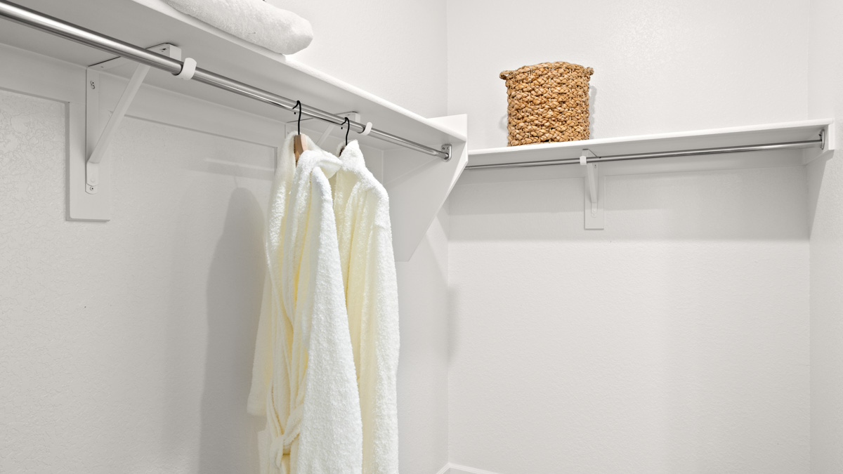 Modern primary bathroom with double vanities, porcelain countertops with a walk-in shower and a walk-in closet.