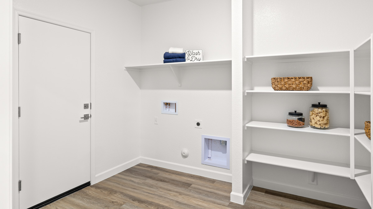 Spacious laundry room with washer and dryer connections and shelving for storage.
