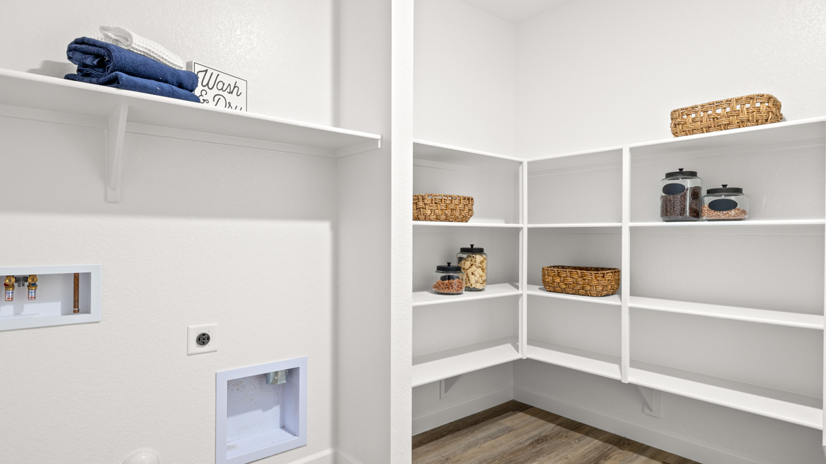 Spacious laundry room with washer and dryer connections and shelving for storage.
