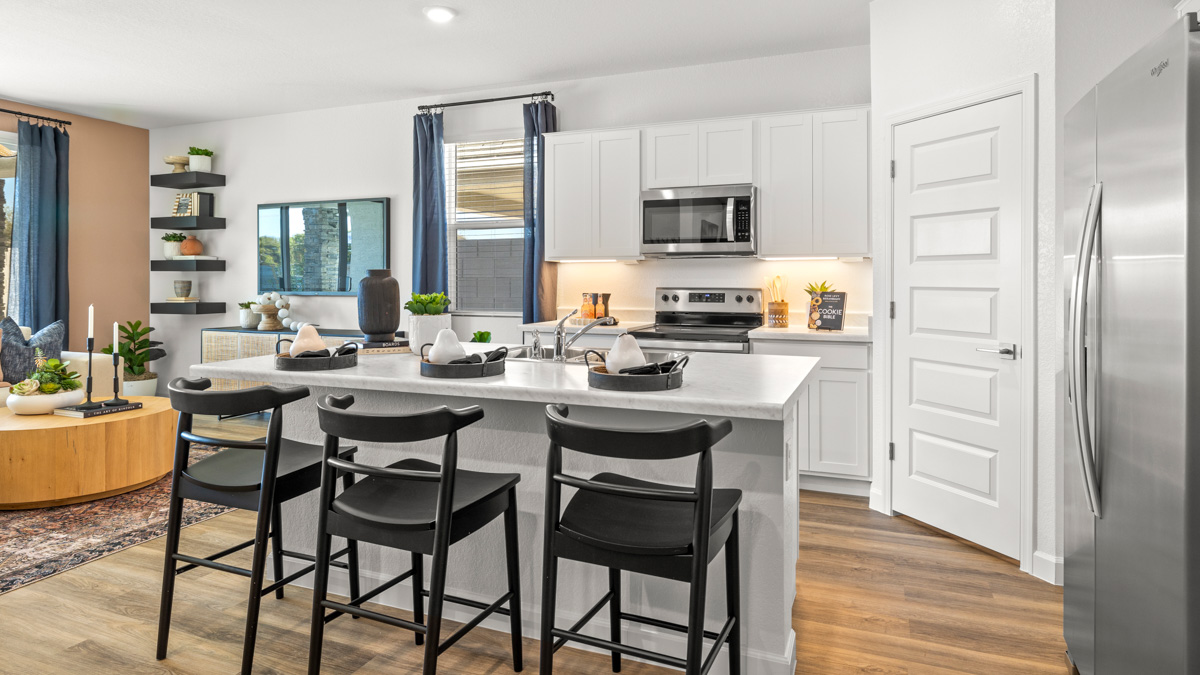 Bright and spacious kitchen with quartz countertops, stainless steel appliances, and an island with bar seating.