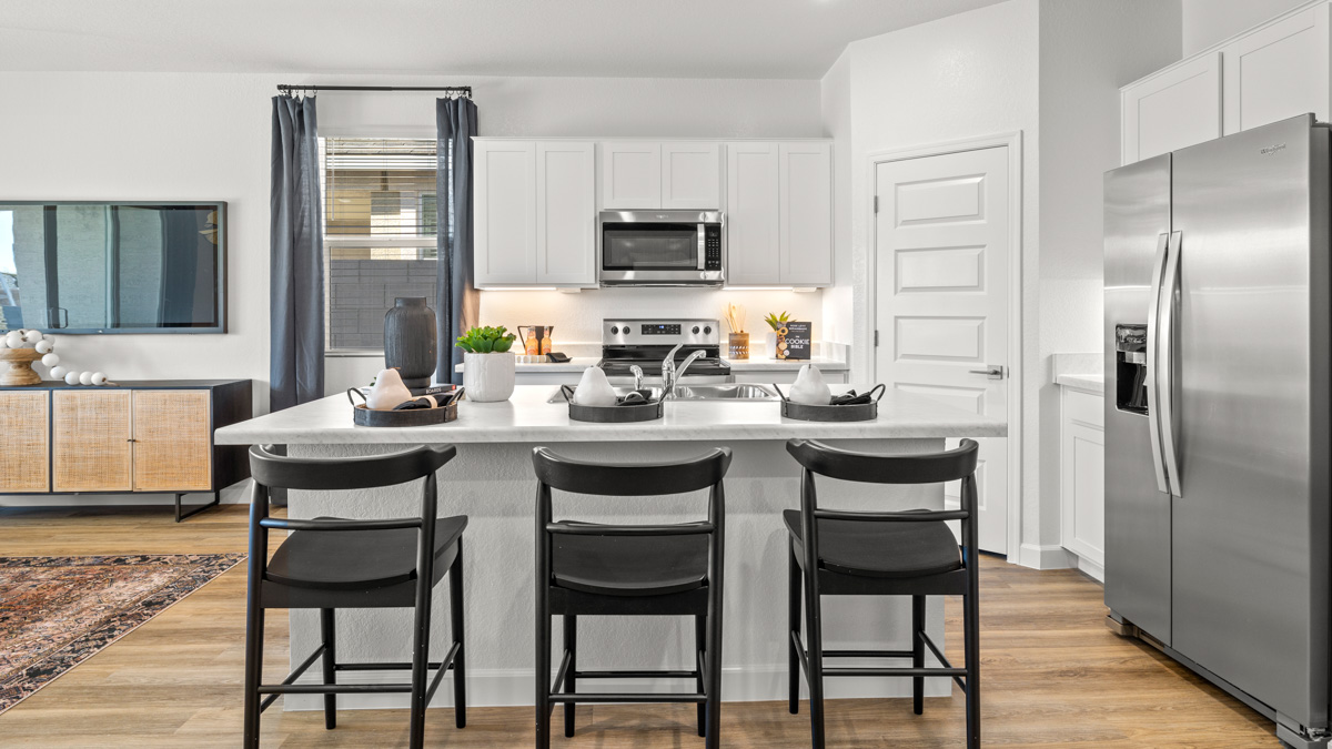Bright and spacious kitchen with quartz countertops, stainless steel appliances, and an island with bar seating.