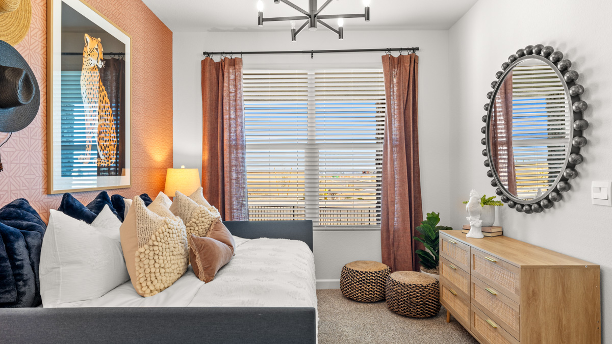 A vibrant kids' bedroom showcasing a neatly made bed, a stylish dresser, and a playful painting that adds charm.