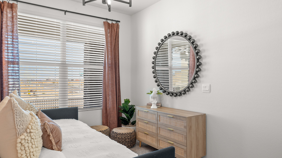 A vibrant kids' bedroom showcasing a neatly made bed, a stylish dresser, and a playful painting that adds charm.