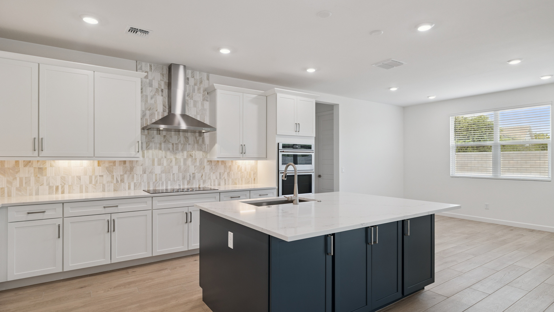 Bright and spacious kitchen with quartz countertops, stainless steel appliances, and an island with bar seating.