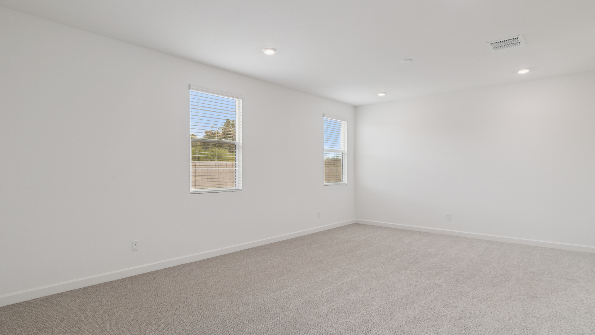 A spacious primary bedroom emphasizing open space and natural lighting.