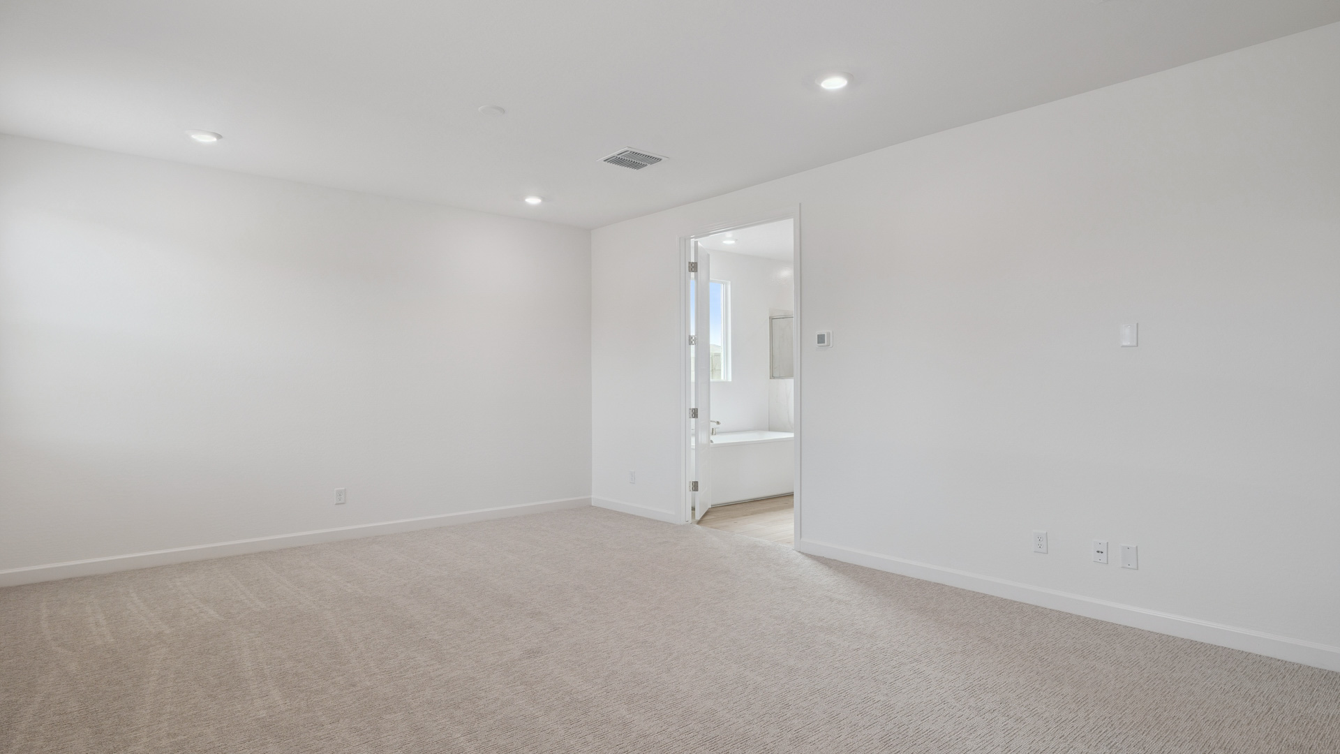 A spacious primary bedroom emphasizing open space and natural lighting.