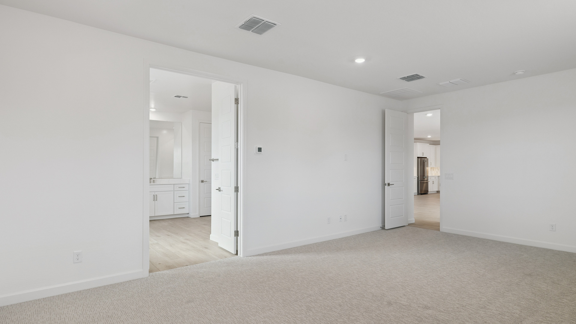 A spacious primary bedroom emphasizing open space and natural lighting.