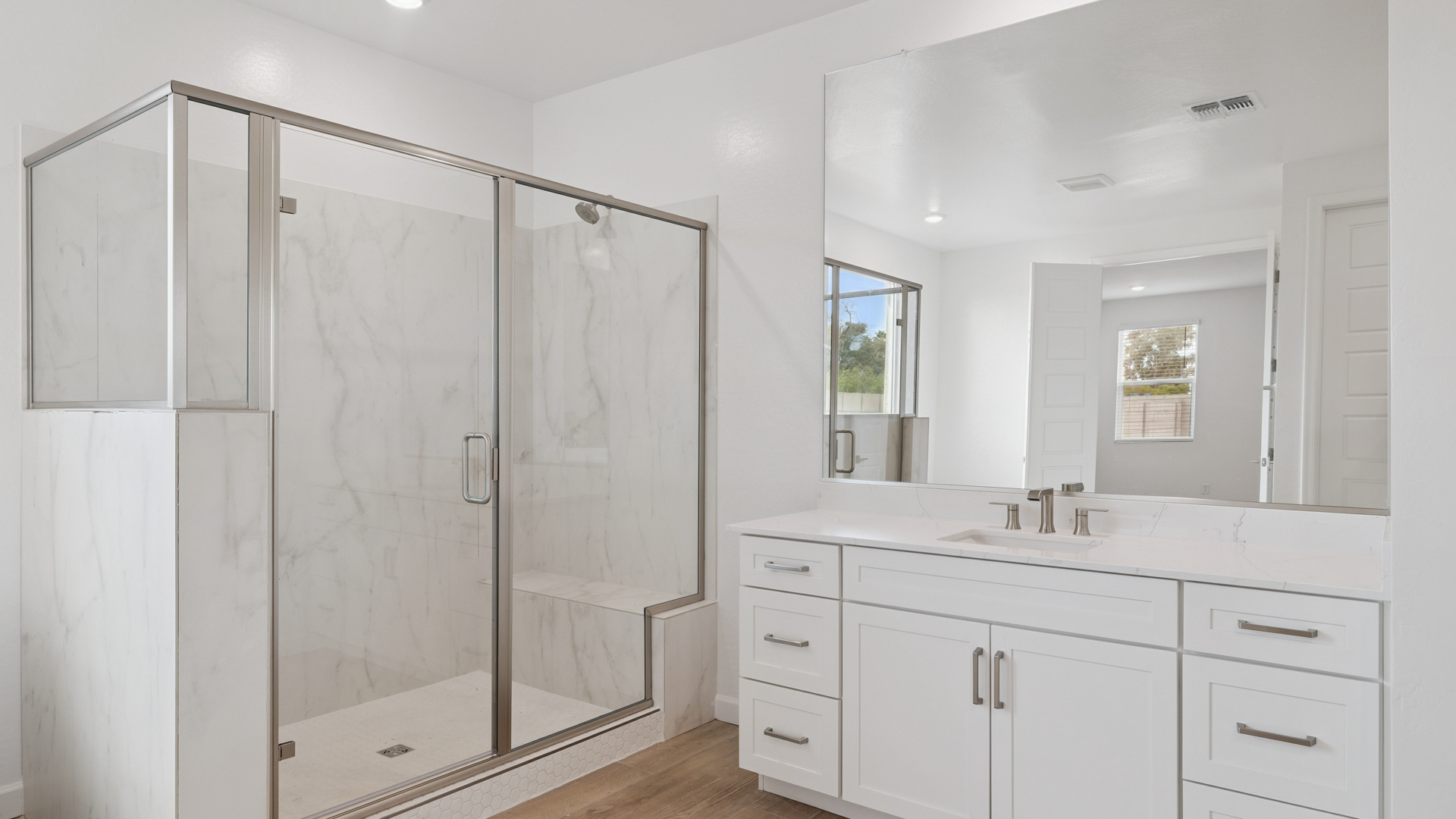 Modern primary bathroom with double vanities, quartz countertops with a walk-in shower and a walk-in closet.