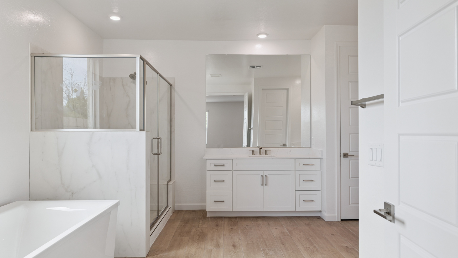 Modern primary bathroom with double vanities, quartz countertops with a walk-in shower and a walk-in closet.