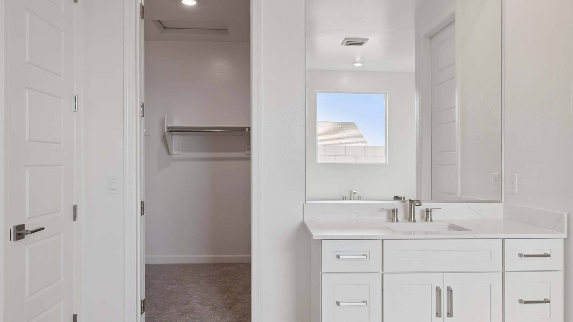 Modern primary bathroom with double vanities, quartz countertops with a walk-in shower and a walk-in closet.