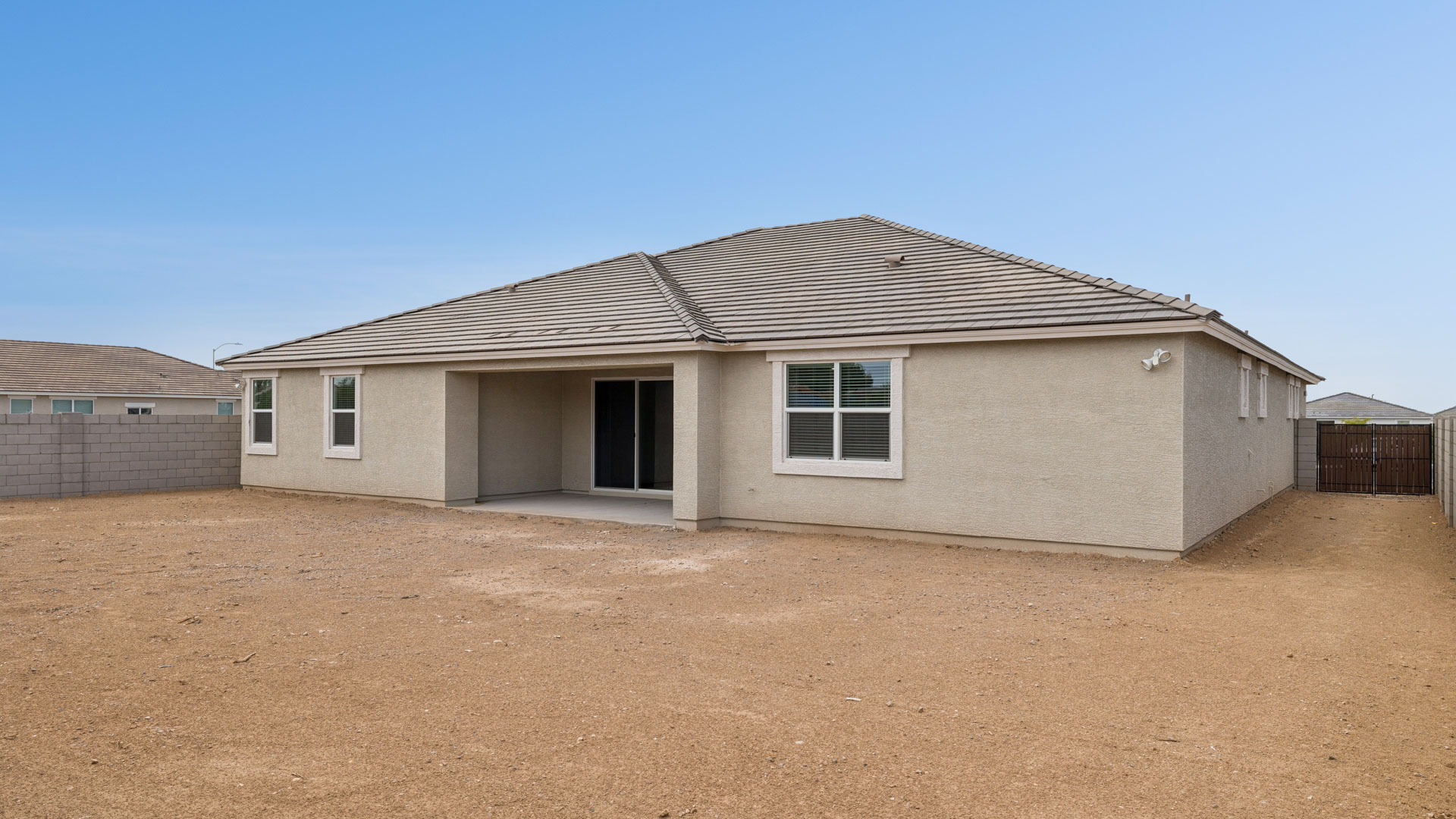Outdoor covered patio with seating area overlooking a well-maintained lawn, perfect for relaxation.