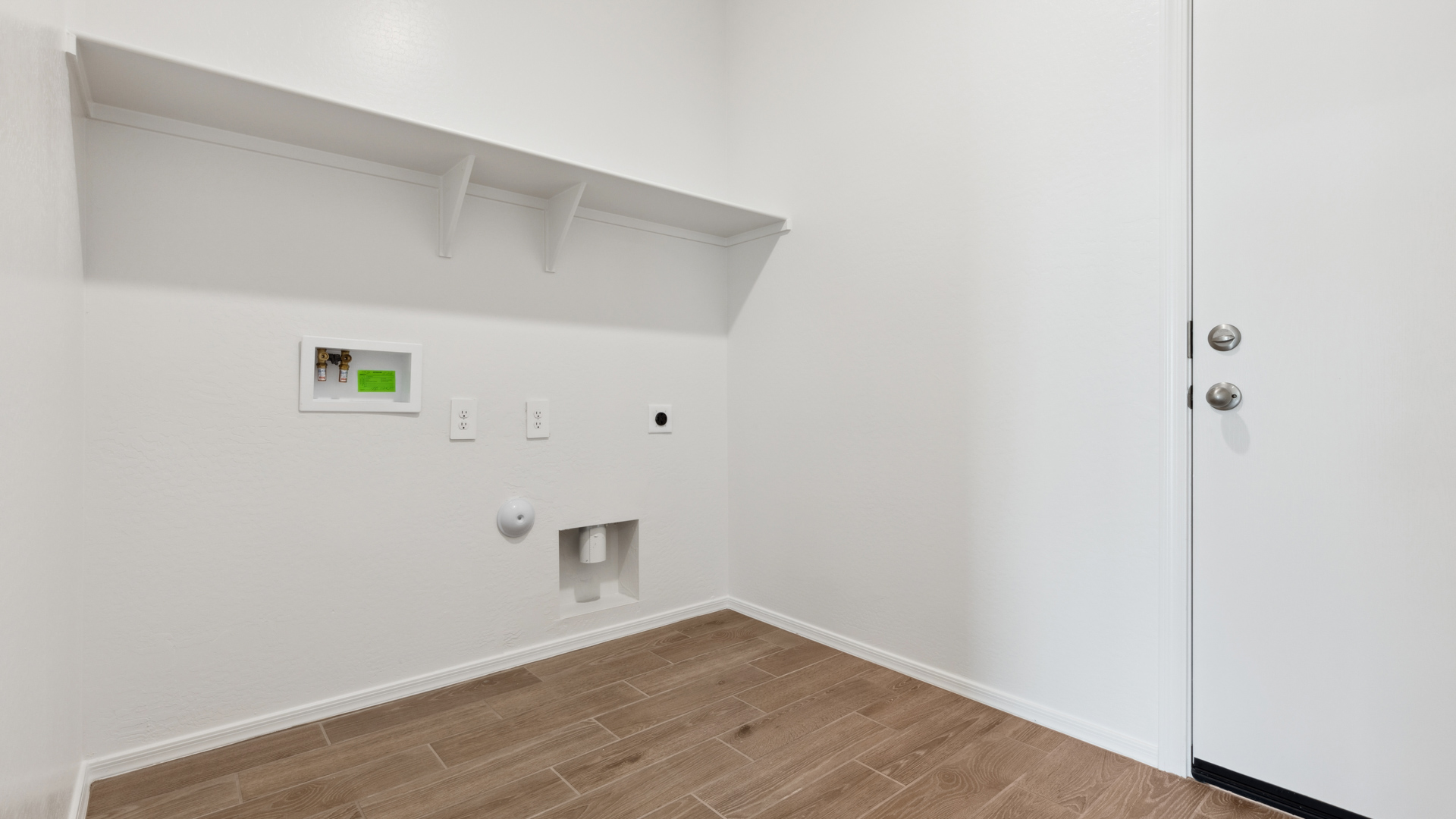 Spacious laundry room with washer and dryer connections and shelving for storage.