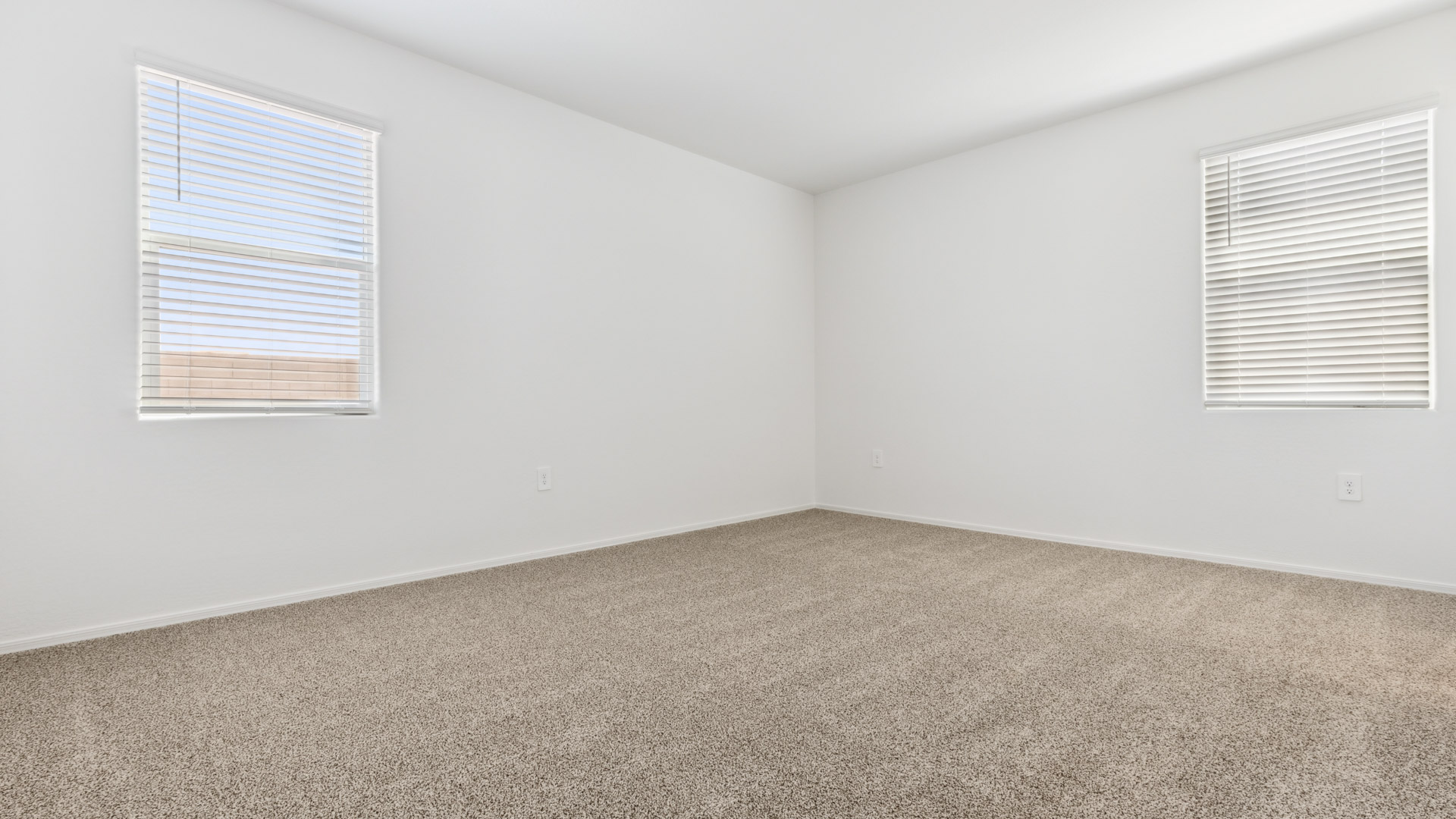 A spacious primary bedroom emphasizing open space and natural lighting.